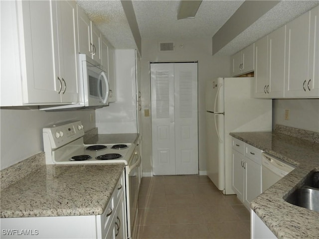 13621 Eagle Ridge Dr Unit 1518, Fort Myers, FL 33912 - kitchen featuring light tile patterned flooring, a textured ceiling, visible vents, white appliances, and white cabinetry