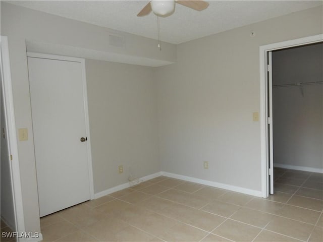 13621 Eagle Ridge Dr Unit 1518, Fort Myers, FL 33912 - unfurnished bedroom with a walk in closet, light tile patterned floors, baseboards, a textured ceiling, and a closet