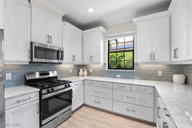 3260 Miyagi Ln, Naples, FL 34114 - kitchen with light wood finished floors, light stone countertops, appliances with stainless steel finishes, white cabinetry, and backsplash