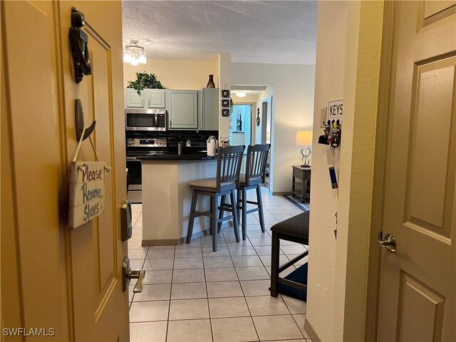 15585 Ocean Walk Cir Unit 216, Fort Myers, FL 33908 - kitchen featuring stainless steel appliances, dark countertops, light tile patterned flooring, tasteful backsplash, and a textured ceiling
