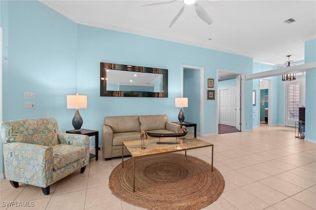 living area with light tile patterned flooring, baseboards, visible vents, ceiling fan, and crown molding