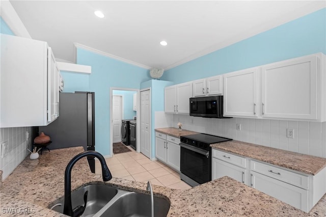kitchen with white cabinets, a sink, separate washer and dryer, decorative backsplash, and black appliances