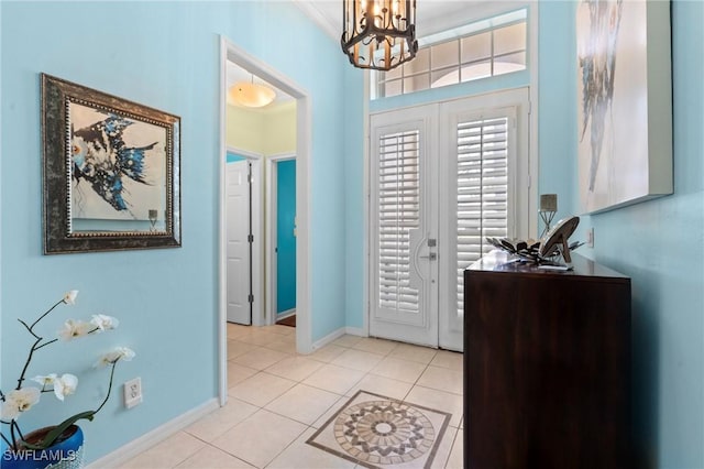 entrance foyer with baseboards, a notable chandelier, and light tile patterned floors