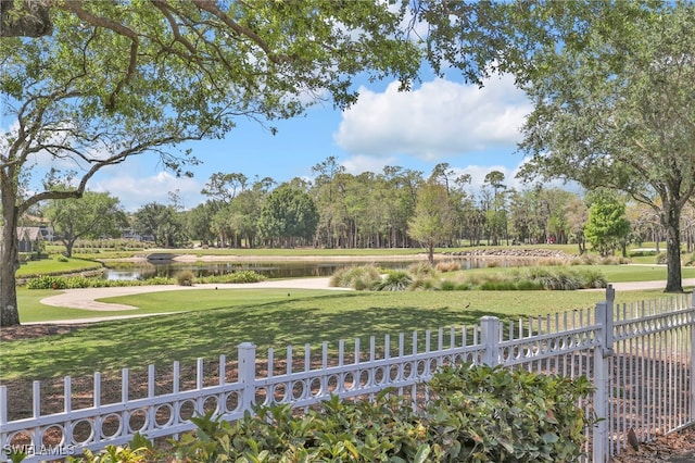 view of community featuring fence, a yard, and a water view