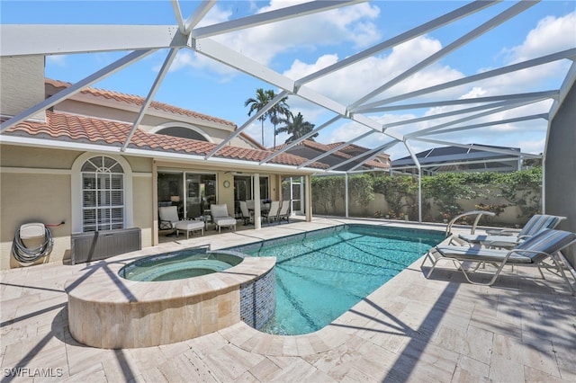 view of pool with glass enclosure, a pool with connected hot tub, and a patio area