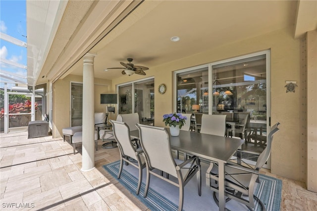 view of patio / terrace with outdoor dining space, a ceiling fan, and glass enclosure