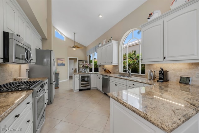 172 Via Napoli, Naples, FL 34105 - kitchen with stainless steel appliances, beverage cooler, a peninsula, a sink, and light stone countertops