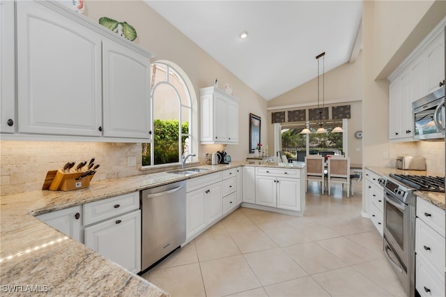 172 Via Napoli, Naples, FL 34105 - kitchen with appliances with stainless steel finishes, backsplash, light stone counters, vaulted ceiling, and white cabinets