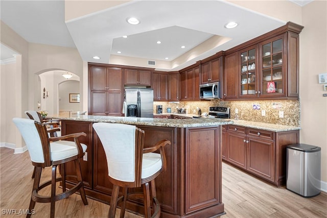 10644 Pelican Preserve Blvd # 101, Fort Myers, FL 33913 - kitchen with arched walkways, stainless steel appliances, backsplash, and light stone counters