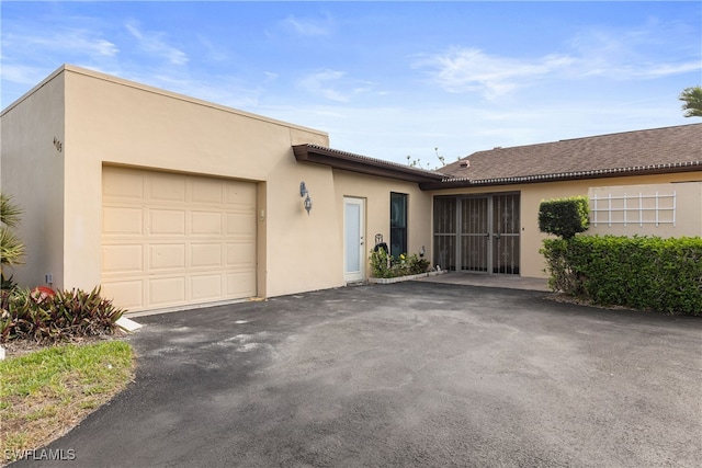 ranch-style home featuring a garage, stucco siding, and aphalt driveway