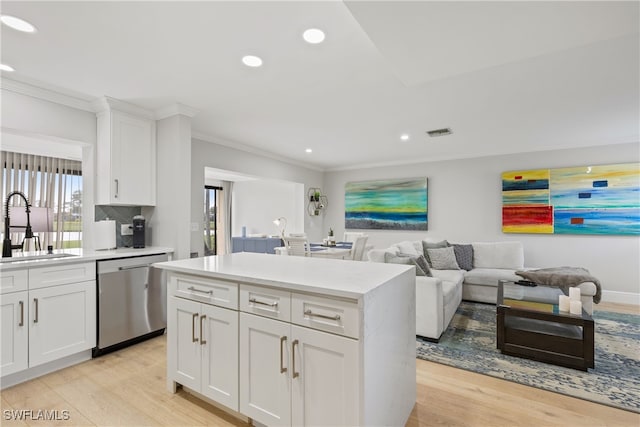 kitchen with a sink, crown molding, light wood finished floors, and stainless steel dishwasher