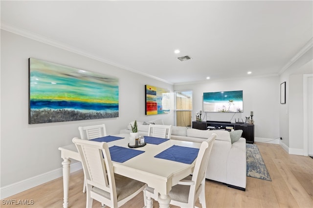dining room with visible vents, light wood-style floors, and crown molding