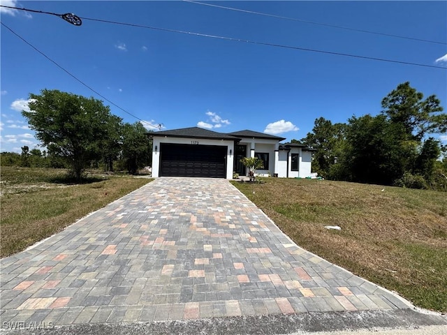 1173 Ebers St E, Lehigh Acres, FL 33974 - view of front of home with an attached garage, a front yard, stucco siding, and decorative driveway