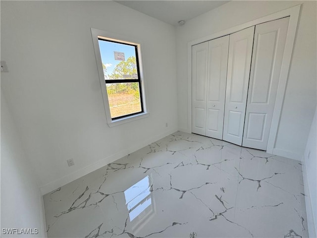 1173 Ebers St E, Lehigh Acres, FL 33974 - unfurnished bedroom featuring a closet, marble finish floor, and baseboards