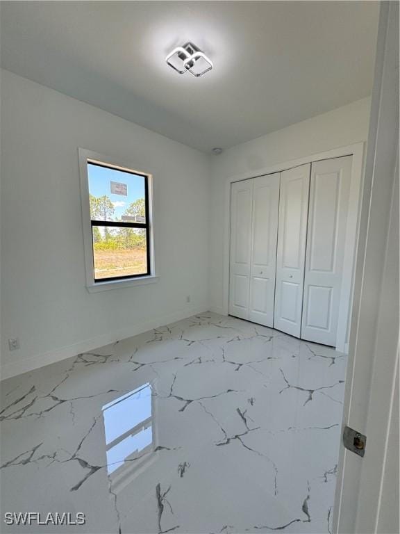 1173 Ebers St E, Lehigh Acres, FL 33974 - unfurnished bedroom with a closet, baseboards, and marble finish floor
