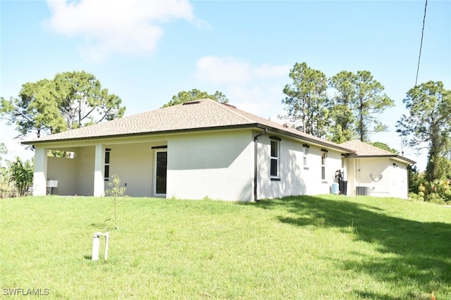 2515 45th St W, Lehigh Acres, FL 33971 - back of house featuring stucco siding, a yard, and central AC