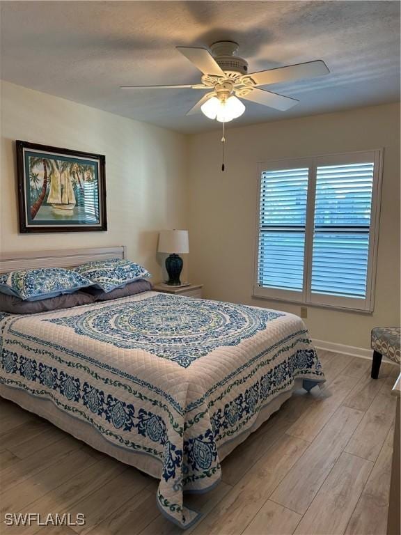4244 SE 20th Pl Unit 218, Cape Coral, FL 33904 - bedroom featuring baseboards, a textured ceiling, a ceiling fan, and light wood-type flooring