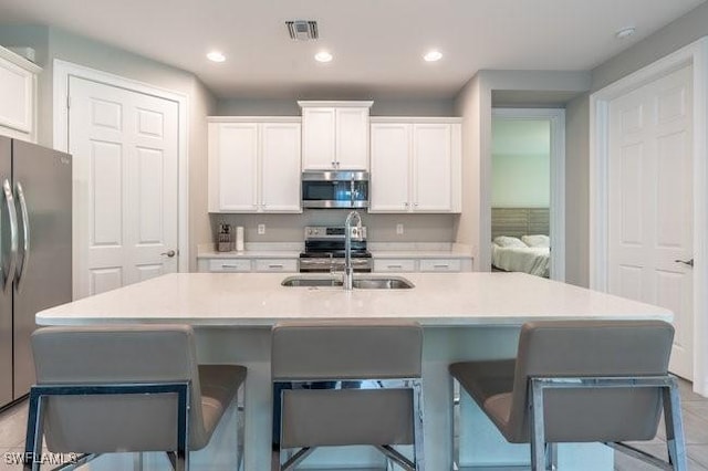 14566 Tropical Dr, Naples, FL 34114 - kitchen with a sink, white cabinetry, visible vents, and stainless steel appliances