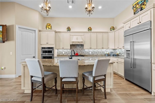 9435 Night Heron Ln, Naples, FL 34120 - kitchen with an inviting chandelier, decorative backsplash, appliances with stainless steel finishes, and visible vents