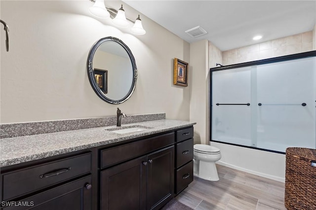 9435 Night Heron Ln, Naples, FL 34120 - full bath with visible vents, combined bath / shower with glass door, toilet, wood finished floors, and vanity