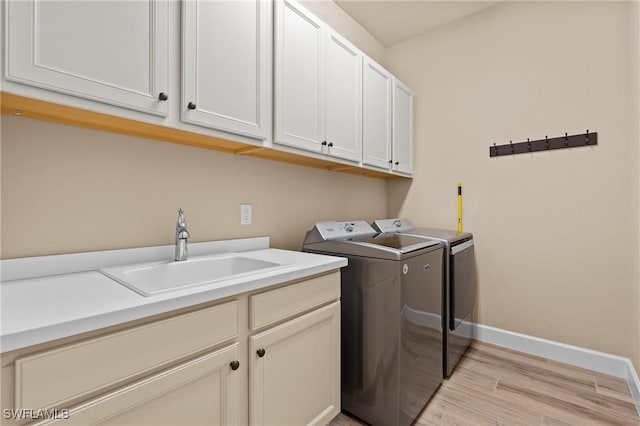 9435 Night Heron Ln, Naples, FL 34120 - laundry room featuring a sink, washing machine and clothes dryer, light wood-type flooring, baseboards, and cabinet space
