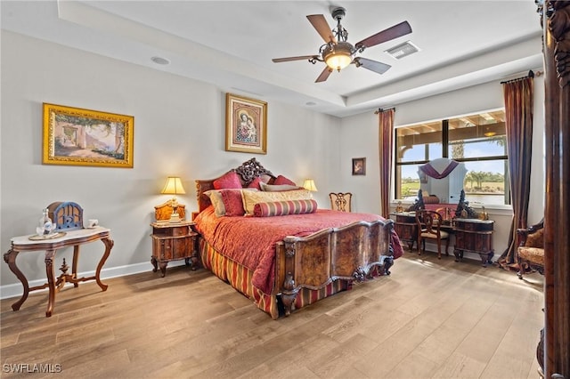 9435 Night Heron Ln, Naples, FL 34120 - bedroom featuring visible vents, baseboards, wood finished floors, a ceiling fan, and a raised ceiling