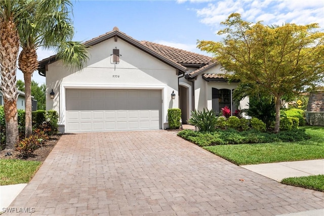 mediterranean / spanish house featuring stucco siding, decorative driveway, an attached garage, and a tile roof