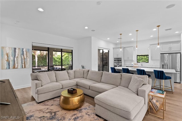 living area with visible vents, a wealth of natural light, light wood finished floors, and recessed lighting
