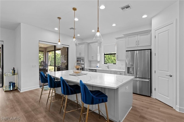 kitchen with a center island, a kitchen breakfast bar, appliances with stainless steel finishes, and plenty of natural light