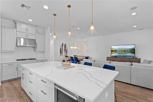 kitchen with beverage cooler, visible vents, under cabinet range hood, open floor plan, and recessed lighting