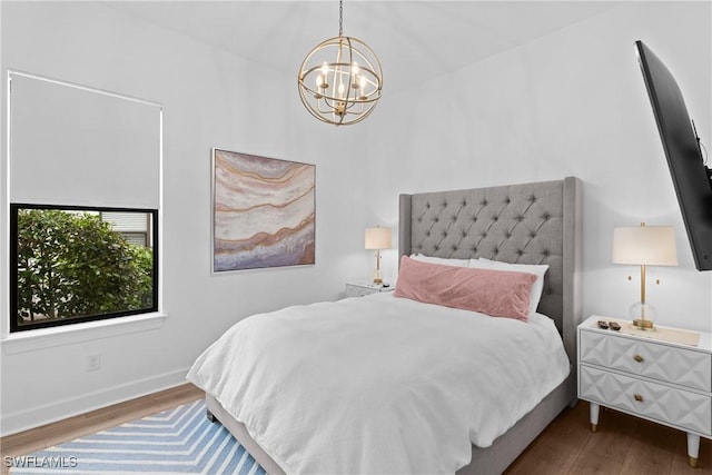 bedroom featuring baseboards, wood finished floors, and an inviting chandelier