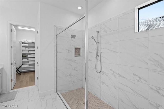 bathroom with recessed lighting, marble finish floor, tiled shower, and a spacious closet