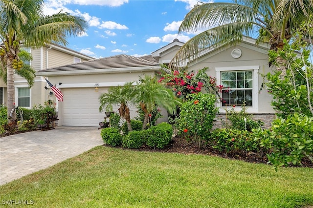 3657 Crimson Ln, Fort Myers, FL 33916 - view of front of house with an attached garage, decorative driveway, a front lawn, stucco siding, and a tiled roof