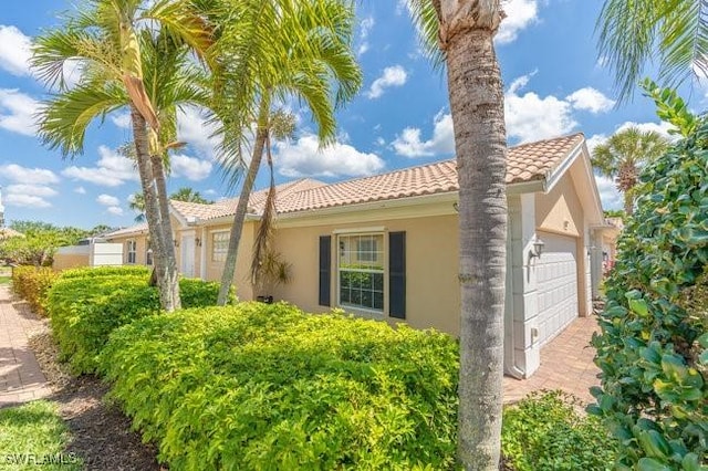7857 Umberto Ct, Naples, FL 34114 - view of property exterior featuring stucco siding, an attached garage, and a tiled roof