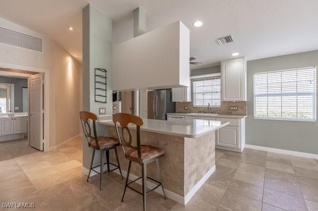 7857 Umberto Ct, Naples, FL 34114 - kitchen featuring a kitchen breakfast bar, light countertops, visible vents, a sink, and freestanding refrigerator