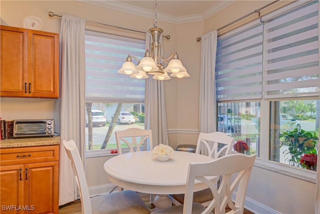 dining space featuring a toaster, a notable chandelier, crown molding, and baseboards