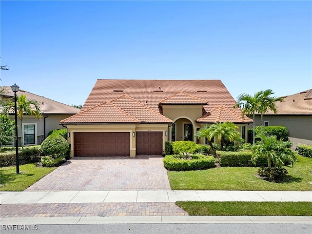 14016 Hawks Eye Ct, Estero, FL 33928 - mediterranean / spanish-style house featuring a tile roof, stucco siding, an attached garage, driveway, and a front yard