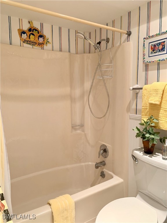 full bath featuring toilet and shower / bath combo with shower curtain