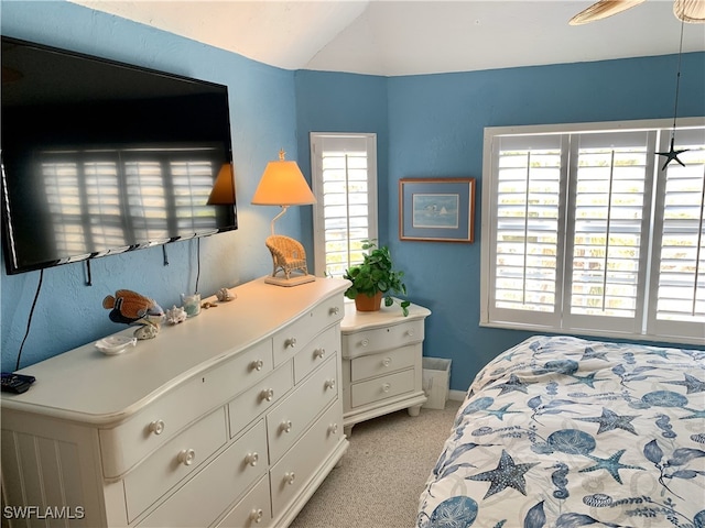 bedroom with baseboards, vaulted ceiling, and light carpet