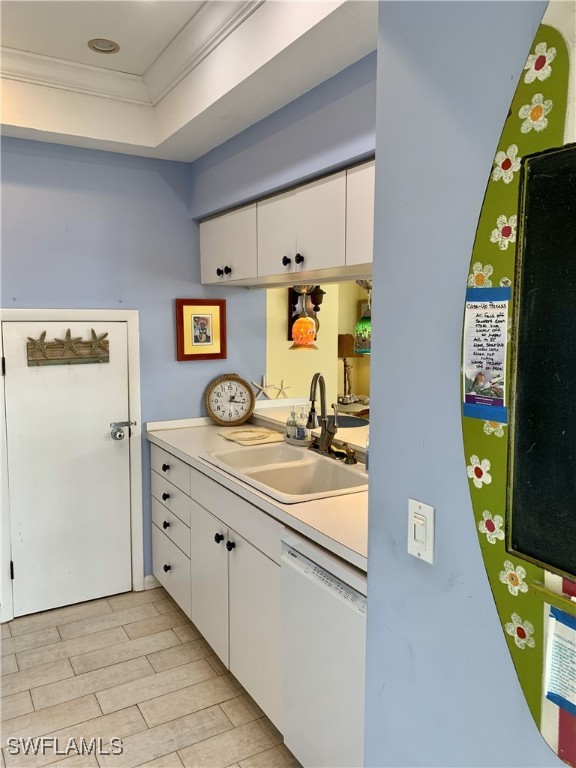 bar featuring white dishwasher, ornamental molding, a sink, and light wood-style floors