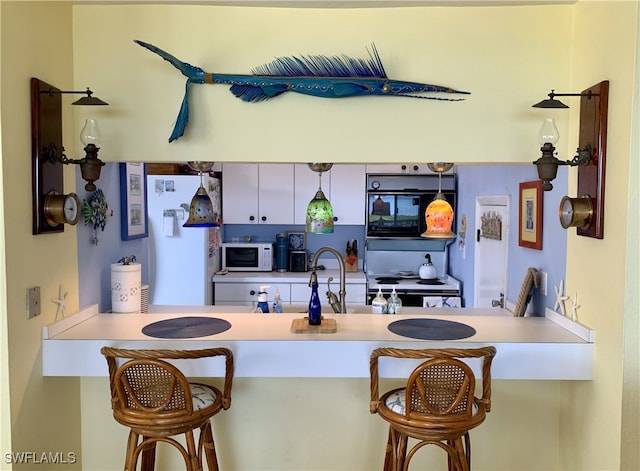 kitchen featuring a peninsula, a breakfast bar, and white appliances