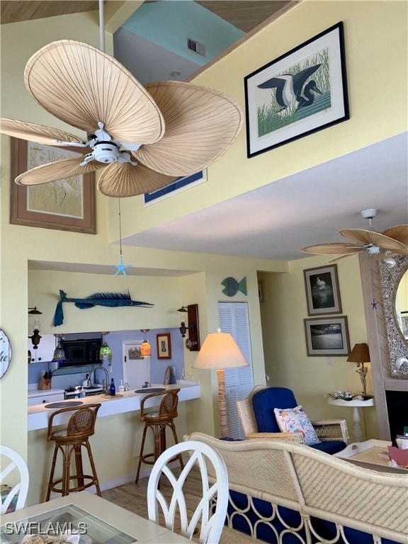 living area featuring visible vents, baseboards, and ceiling fan