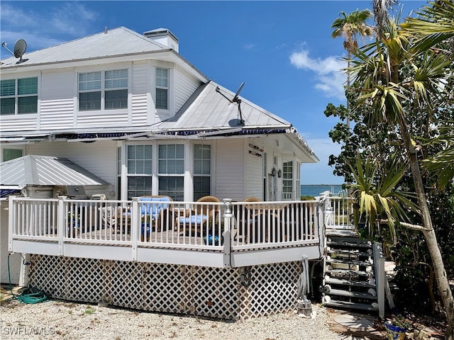 rear view of property featuring a wooden deck and metal roof