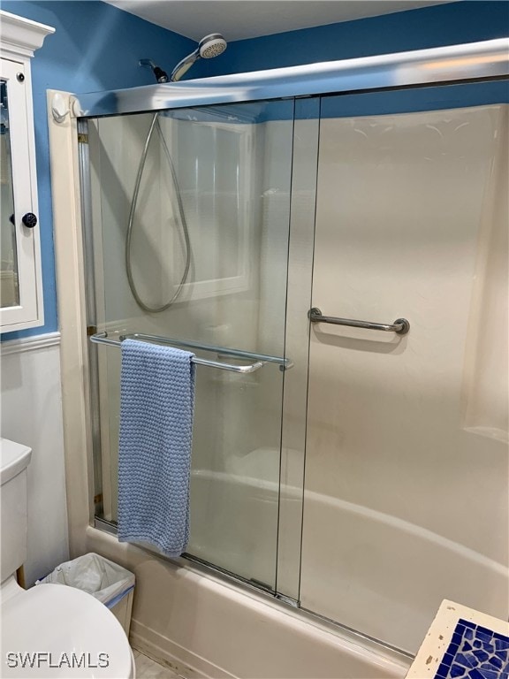 full bath featuring toilet and bath / shower combo with glass door