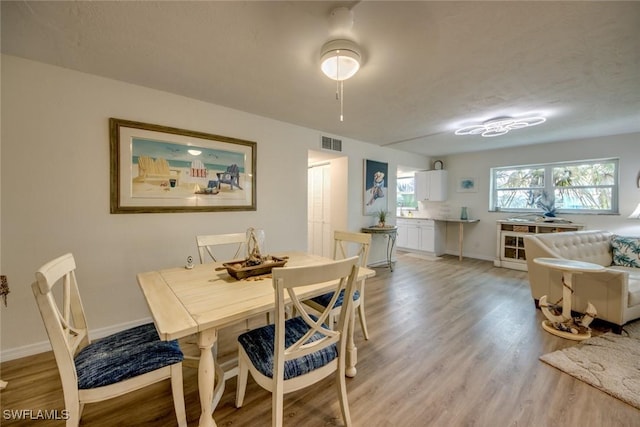 dining room with light wood-type flooring, baseboards, and visible vents