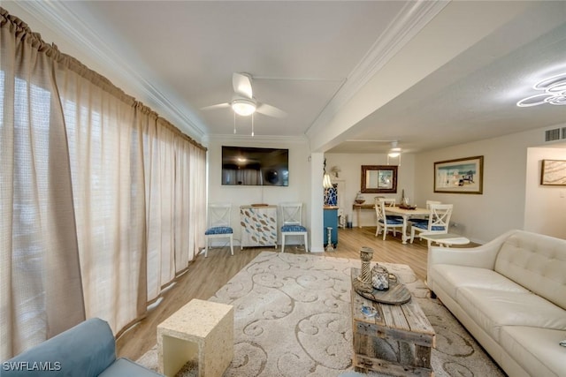 living area with crown molding, wood finished floors, ceiling fan, and visible vents