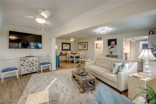 living room with ornamental molding, baseboards, and wood finished floors