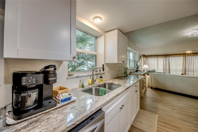 kitchen with light wood-style flooring, a sink, white cabinetry, and light stone countertops