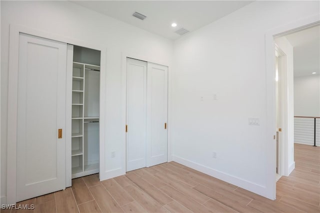 3384 Canal St, Naples, FL 34112 - unfurnished bedroom featuring two closets, visible vents, light wood-style flooring, and baseboards