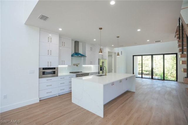 3384 Canal St, Naples, FL 34112 - kitchen featuring visible vents, a sink, white cabinetry, wall chimney range hood, and stainless steel appliances